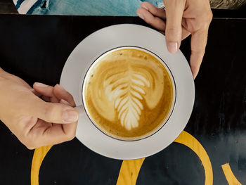 Midsection of woman holding coffee cup on table