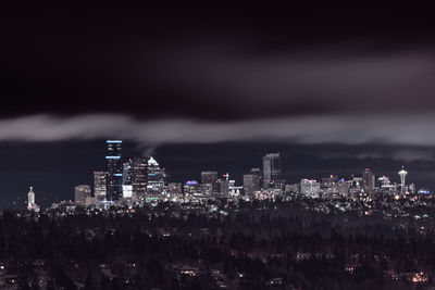 Illuminated buildings in city against sky at night