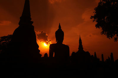 Silhouette of buddha statue against sky during sunset