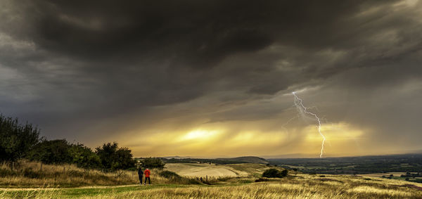 Scenic view of field against storm clouds