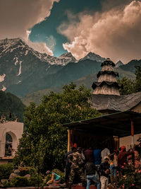 Group of people by buildings against mountains