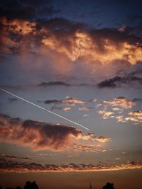 Low angle view of vapor trails in sky during sunset