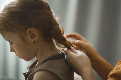 Mother braiding daughter's hair at home