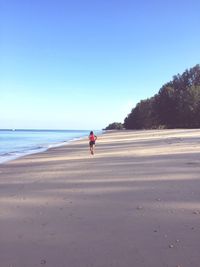 Man on beach against clear sky