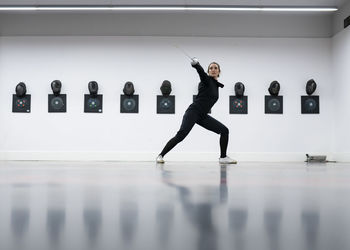 Woman in fencing outfit practicing at gym