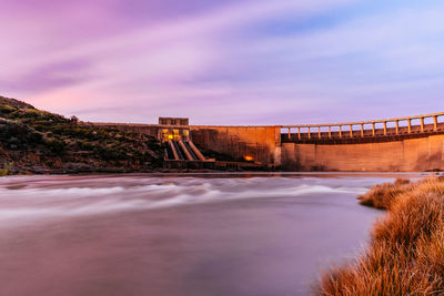 Bridge over river against sky during sunset