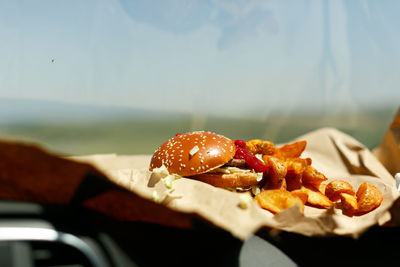 Woman's hands eating a hamburger inside a car, fast food