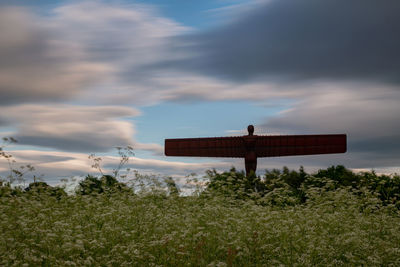 Cross on field against sky