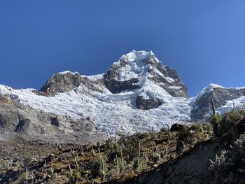 Low angle view of snowcapped mountain against clear blue sky