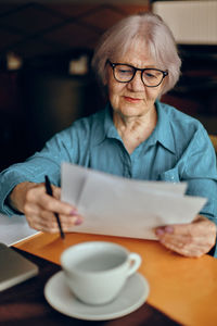 Senior businesswoman reading document in cafe