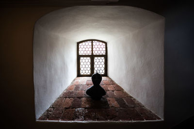 Rear view of man on cross against wall in building
