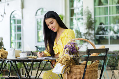 Beautiful woman sits writing on note book in garden