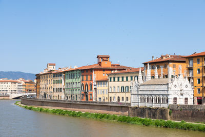 Buildings by river against clear sky