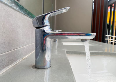 Close-up of faucet on table against wall