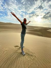 Full length of man walking on sand at beach against sky