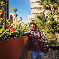 Portrait of smiling young woman standing against plants