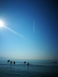 People in sea against clear blue sky