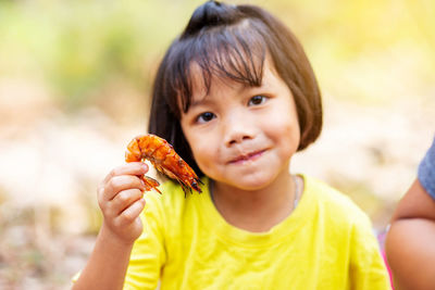 Portrait of cute smiling girl holding shrimp