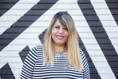 Portrait of smiling woman standing against wall