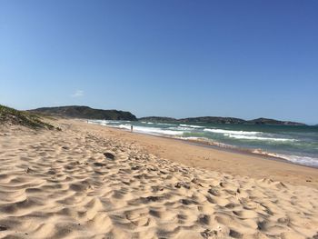 Scenic view of beach against clear blue sky