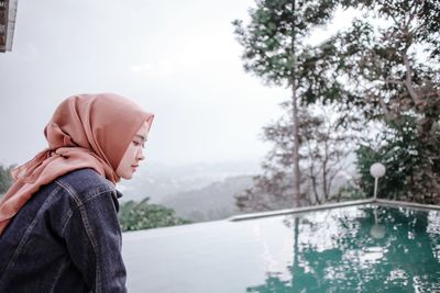 Side view of woman wearing hijab looking at infinity pool