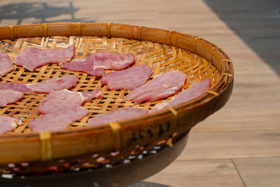 Close-up many pieces of raw pork on the bamboo basket drying by the light of sun