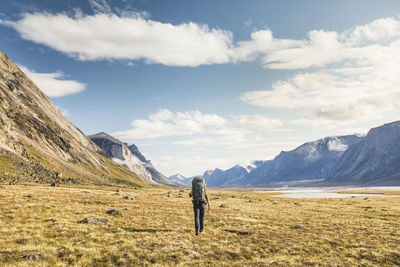 Rear view of backpacker crosses arctic tundra