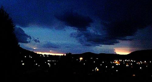 View of illuminated mountain range against cloudy sky