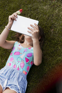 Girl lying on lawn and using digital tablet