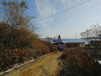 Road by buildings against sky during autumn