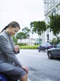 Side view of businesswoman checking time on sidewalk