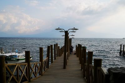 Wooden posts on pier over sea against sky