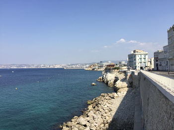 Scenic view of sea by city buildings against sky