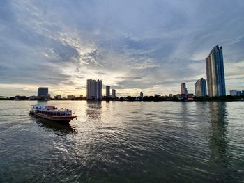 Nautical vessel on sea against modern buildings in city