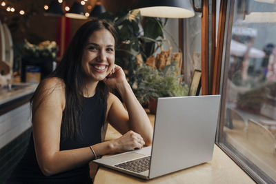 Young woman smiling sitting with laptop in cafe
