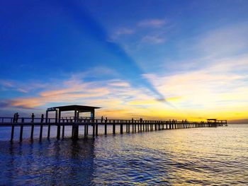 Pier on sea against sky during sunset