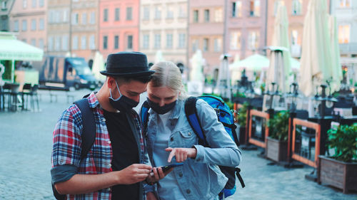 Rear view of man using mobile phone in city