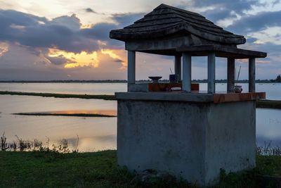 Built structure on beach against sky during sunset