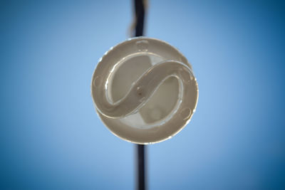 Close-up of light bulb against blue sky