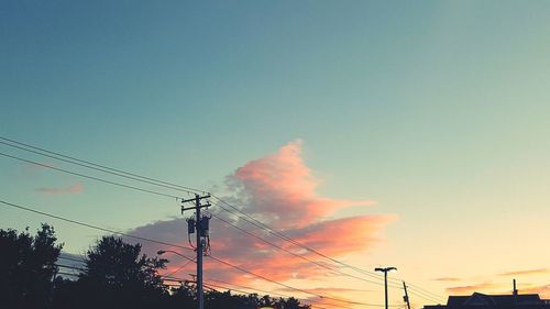 Low angle view of electricity pylon against cloudy sky