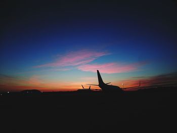 Silhouette of airplane against sky during sunset