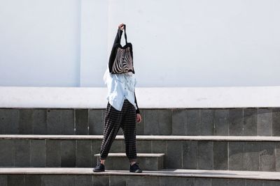 Rear view of woman standing against wall