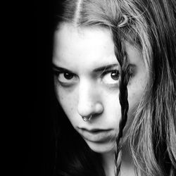 Close-up portrait of beautiful woman against black background