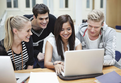 Young happy friends using laptop