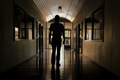 Rear view of silhouette man standing in corridor