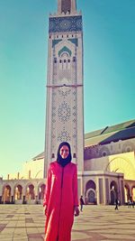 Portrait of smiling young woman standing against blue sky