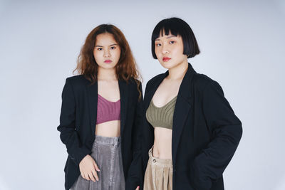 Portrait of lesbian couple standing against gray background