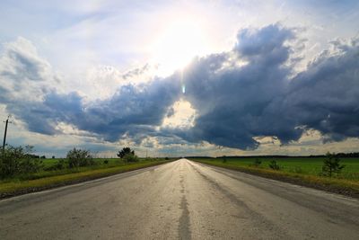 Empty road amidst land against sky