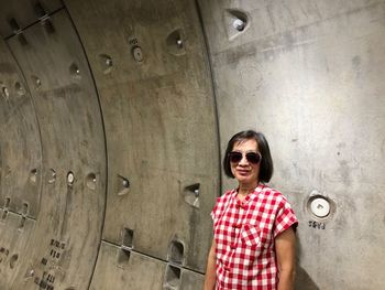 Portrait of young woman wearing sunglasses standing in tunnel