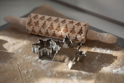 High angle view of rolling pin and cookie cutters on cutting board